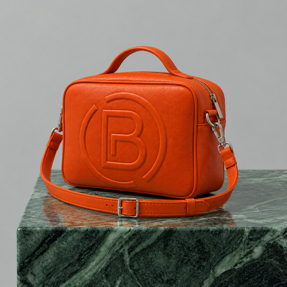 Bottega Paesano Pouch arancione, vista a tre quarti con tracolla su piano in marmo verde