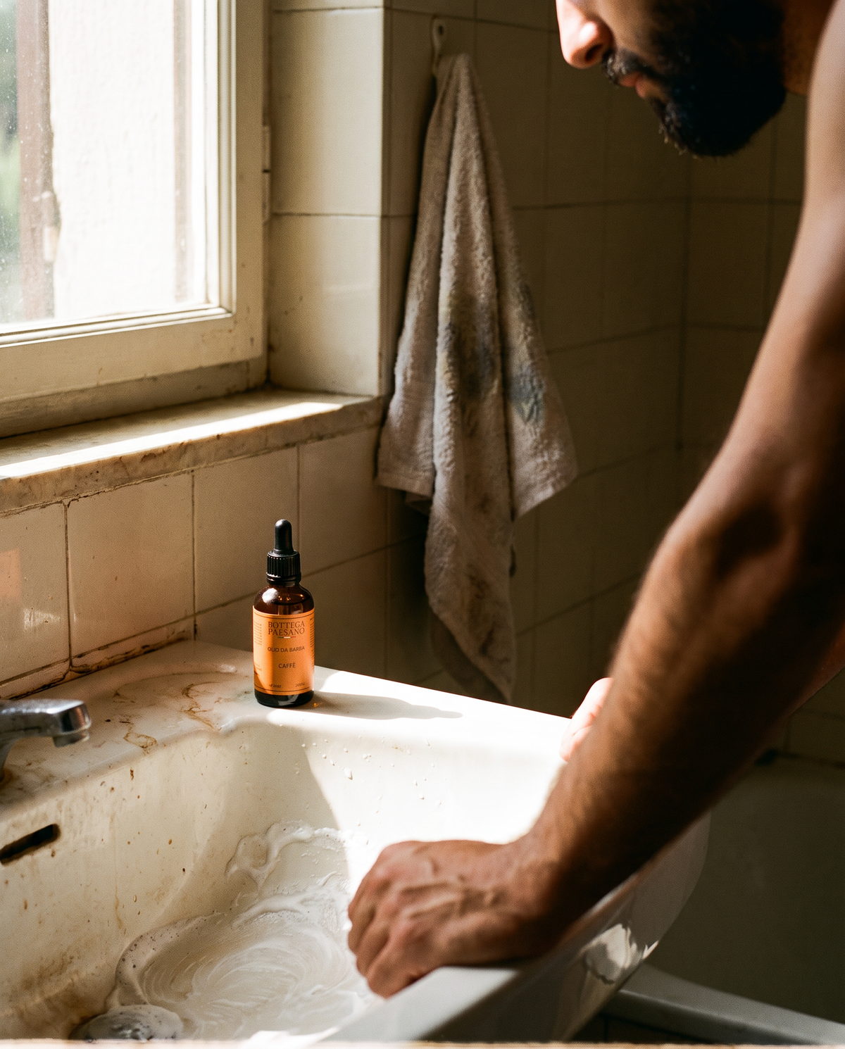Uomo al lavabo dopo la rasatura, prodotto barba Bottega Paesano sul bordo