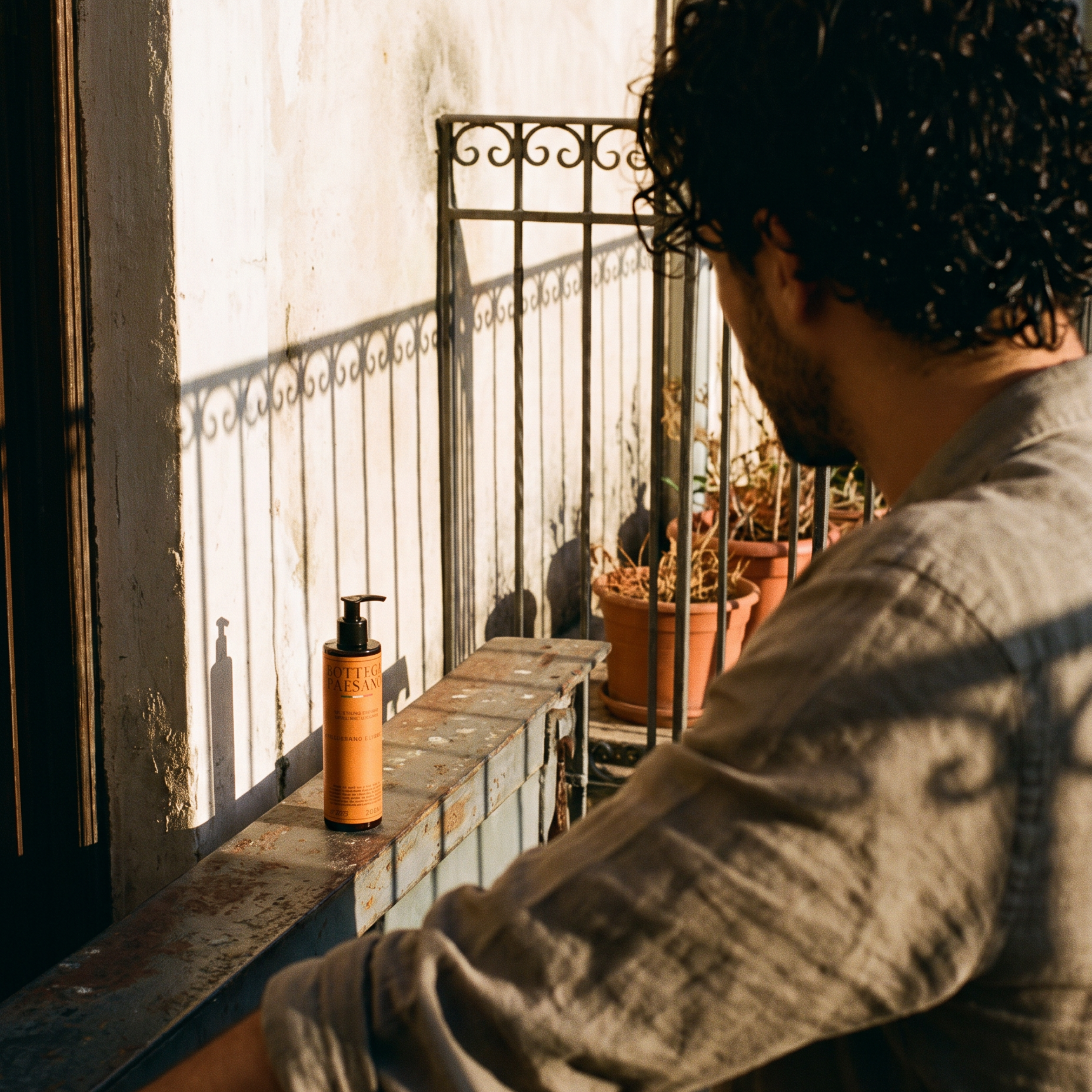 Uomo con capelli ricci sul balcone al sole, prodotto per ricci Bottega Paesano