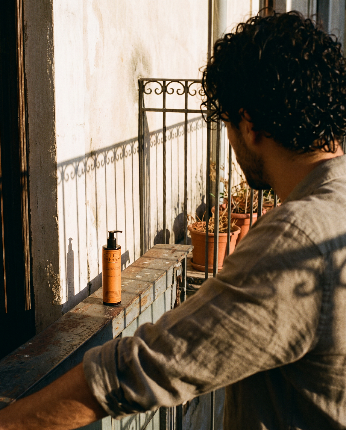 Uomo con capelli ricci sul balcone al sole, prodotto per ricci Bottega Paesano