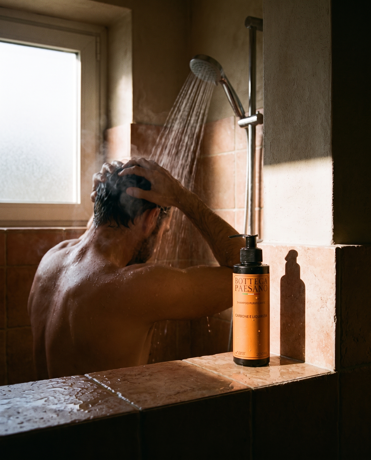 Uomo sotto la doccia si lava i capelli, shampoo purificante Bottega Paesano